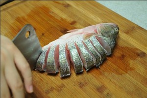 將鱸魚(yú)清洗干凈，從脊椎處切斷至腹部，腹部保留1cm左右不要切斷。