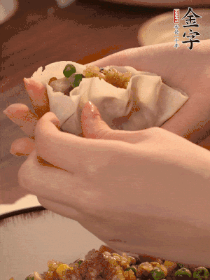 取一大勺餡料放進(jìn)餃子皮里，用大拇指按住頂部餡料，再用虎口掐出形狀。